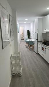 a white kitchen with a table and a dining room at Apartamento con terraza sol y montaña tranquilidad in Málaga