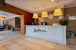a hotel lobby with a reception counter and pendant lights at Radisson Hotel Old Town Riga in Rīga