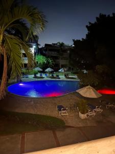 a swimming pool at night with chairs and umbrellas at Antiguo Dominican Bay in Boca Chica