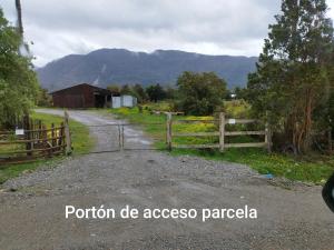 a dirt road with a fence and a barn at Tiny Home El descanso del Pescador in Puerto Cisnes
