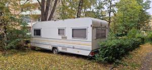 a white trailer parked in a field with trees at Beheizter Wohnwagen mit Küche und Duschbad in Berlin +7 photos
