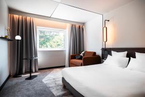 una habitación de hotel con una cama y una silla en Novotel Belfort Centre Atria, en Belfort 111 fotos más
