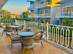 a balcony with tables and chairs and a building at Creek Nest Resort in Rāmnagar