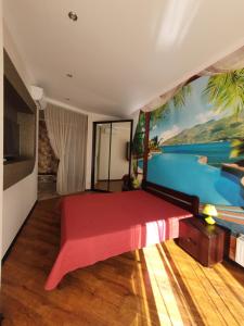a bedroom with a red bed with a painting on the wall at Квартира Аркадия ЖК жемчужина Кадора 10 мин от моря in Odesa