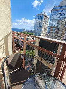 a table and a chair on a balcony with buildings at Квартира Аркадия ЖК жемчужина Кадора 10 мин от моря in Odesa