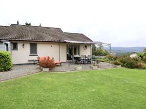 a white house with a patio and a grass yard at Coeur de Biche in Rendeux