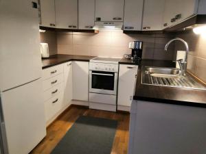 une cuisine avec des armoires blanches et un évier dans l'établissement Convenient Apartment for 2, à Kemi