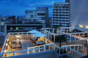 Un balcón con mesas y sombrillas en un edificio. en Normandy Hotel, en Belo Horizonte