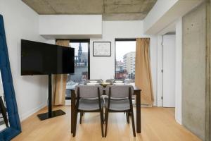 a dining room with a table with chairs and a flat screen tv at Chic Hideaway - Downtown Hotspot in Montréal