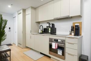 a kitchen with white cabinets and a stove top oven at Chic Hideaway - Downtown Hotspot in Montréal +11 photos