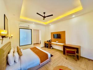 a bedroom with a bed and a desk and a tv at Creek Nest Resort in Rāmnagar