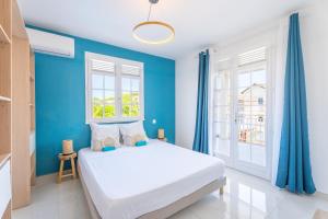a blue bedroom with a white bed and blue walls at Villa Rose Du Désert in Sainte-Anne +39 photos