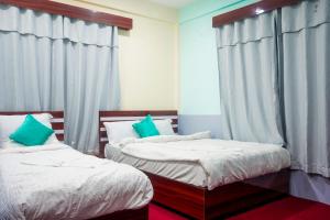- 2 lits dans une chambre dotée de rideaux bleus dans l'établissement Manthali Park Inn, à Rāmechhāp