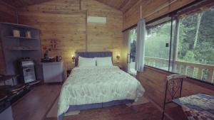 a bedroom with a bed in a wooden cabin at Pousada Kaporã in Bocaiúva do Sul