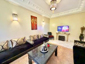 a living room with a couch and a tv at Spacieux & confortable, parfait pour familles ou séjours tranquilles in Marrakech