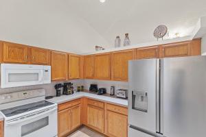 a kitchen with white appliances and wooden cabinets at Life is Good! in Port Saint Lucie +30 photos