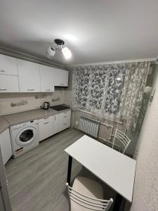 a kitchen with white cabinets and a table with chairs at Buiucani in Chişinău