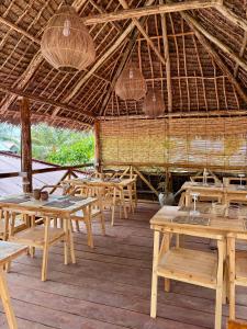 a restaurant with wooden tables and chairs in a straw roof at Kasuku Villa in Dimbuni