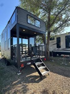 a black tiny house sitting next to a tree at Prairie Dog Perch Tiny Home in Interior
