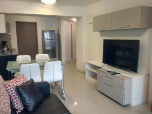 un salon avec une télévision et une table avec des chaises blanches dans l'établissement Solares de Araus 103, à Colonia del Sacramento