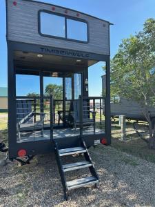 a tiny house with a porch and a staircase at Coyote Crossing Tiny Home in Interior