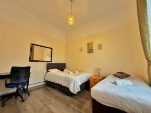 a bedroom with two beds and a desk and a chair at Near City-Birkenhead rooms in Birkenhead +9 photos