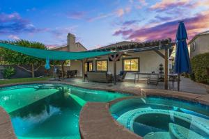 una piscina con una sombrilla y una casa en Empire Polo Grounds Close Gorgeous pool and spa home bike to Coachella, en Coachella