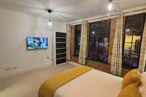 a bedroom with a bed and a tv on a wall at Downtown Loughborough Escape 3BR Flat for 6 Guests in Loughborough