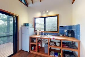 a kitchen with a sink and a white refrigerator at Mahogany Cabaña at Inn The Trees -Gold Standard Certified in Placencia Village