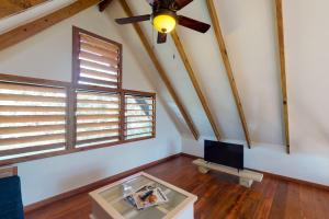 a living room with a ceiling fan and a table at Mahogany Cabaña at Inn The Trees -Gold Standard Certified in Placencia Village