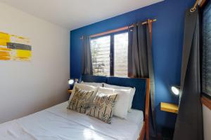 a bedroom with a blue wall and a bed with pillows at Mahogany Cabaña at Inn The Trees -Gold Standard Certified in Placencia Village +14 photos