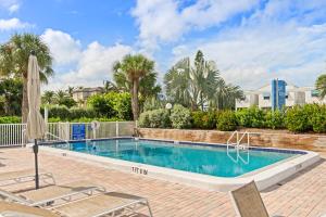 una piscina con dos sillas y una sombrilla en Gulf Tides of Longboat Key, en Longboat Key 22 fotos más