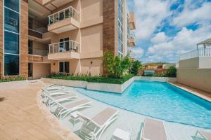a swimming pool with chairs and a building at AtMonchi Stylish Condo in Palm-Eagle Beach
