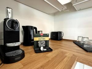 a coffee maker with a box on a wooden floor at HolidayHome Apartments I Airport Deluxe Condo with Terrace in Schönefeld +24 photos