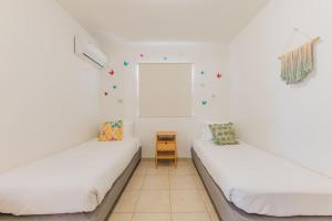 two beds in a white room with a window at Charming hideaway 2 min to Beach in Palm-Eagle Beach +40 photos
