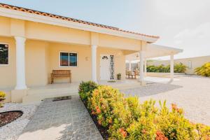 a house with a porch and a bench in a yard at Charming hideaway 2 min to Beach in Palm-Eagle Beach