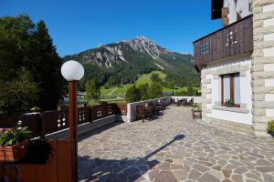 a building with a patio with a mountain in the background at Villa Alpina Hotel in Forni di Sopra