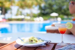 a plate of food and a drink on a table near a pool at Casa Oasis B-Nayar Gated, Beach Club, Free Shuttle in Cruz de Huanacaxtle