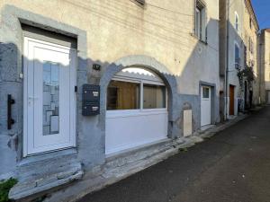 un edificio con puertas blancas y una ventana arqueada en Studio Glamour avec espace balnéo privé, en Dallet