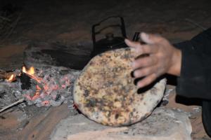 a person is cooking a pizza on a grill at Enad desert camp in Wadi Rum +46 photos