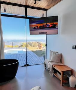 a bedroom with a large tv and a bed and a tub at Vista espetacular, piscina e banheira no quarto! in Maria da Fé