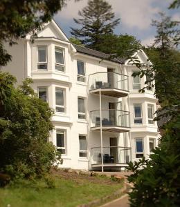 a large white building with a balcony in front of it at Allt Nan Ros Apartments fort william in Onich