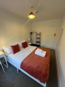 a bedroom with a large bed with red and white pillows at Cosy 2 Bed Maisonette near Heathrow & Windsor in Staines +15 photos