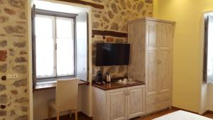 une pièce avec une télévision et une armoire avec une fenêtre dans l'établissement Manolia, à Hydra