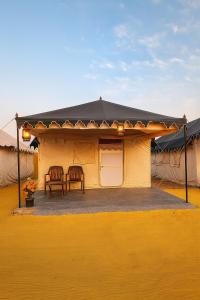 a yellow house with a black roof and a table and chairs at Stayguru Patgar Tent in Dhordo