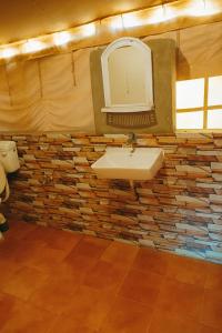 a bathroom with a sink and a stone wall at Stayguru Patgar Tent in Dhordo