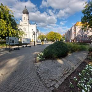 una calle con un edificio blanco con una torre de reloj en Gold Moon Apartment, en Kecskemét 7 fotos más