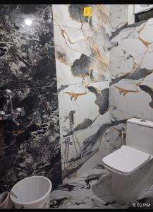 a bathroom with a toilet and a marble wall at YR Heights Home Stay in Hyderabad