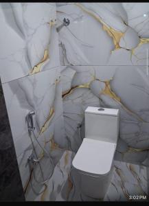 a bathroom with a toilet and a marble wall at YR Heights Home Stay in Hyderabad +8 photos