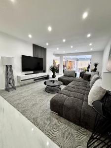 a living room with a large couch and a flat screen tv at Villa élégante avec piscine à Cluny Schoelcher in Schœlcher